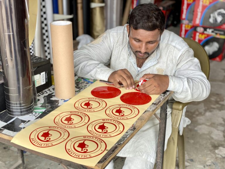 Artisan focuses on creating custom stickers at a workshop table.